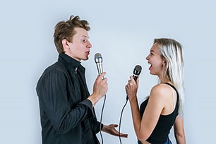 An illustration of a man and a woman holding microphones and looking at each other, representing effective communication in a relationship.
